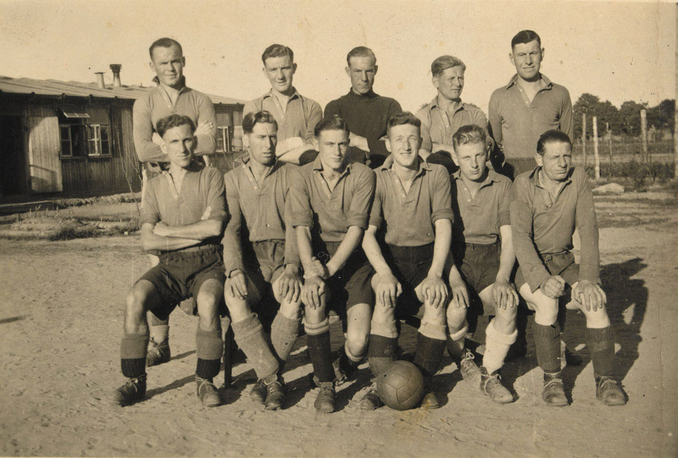 Stalag XX B, obóz jeniecki. Drużyna piłkarska. W tle barak obowozowy. 